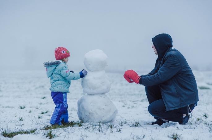 Pai e filha constroem um boneco de neve