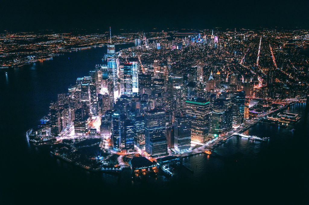 Nova York vista de cima durante a noite, com as luzes dos prédios iluminando a cidade.