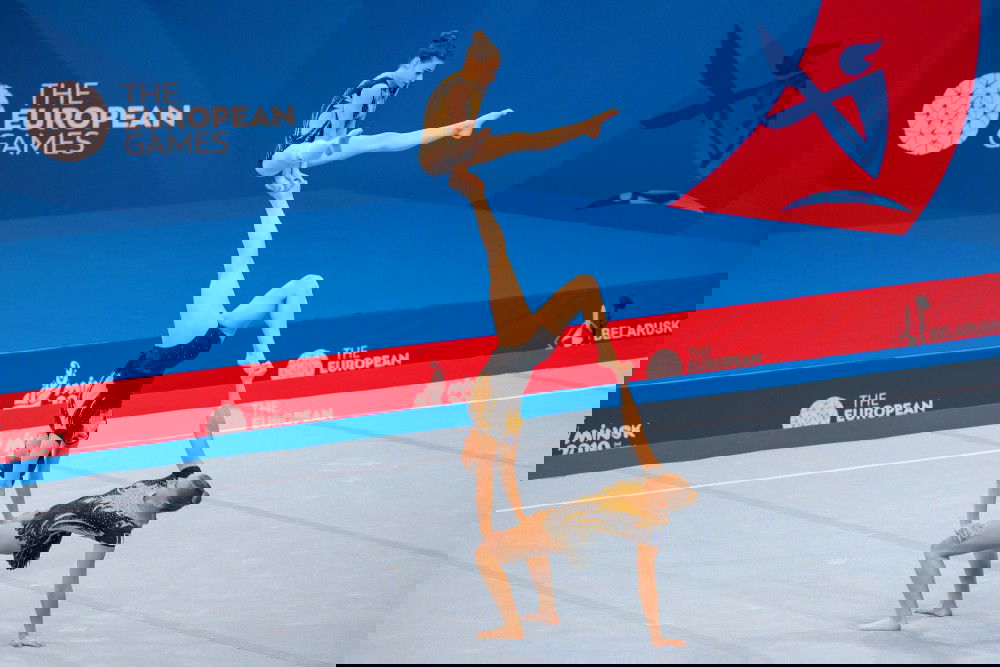 Três ginastas acrobáticas se sustentam uma sobre a outra em uma competição da modalidade.