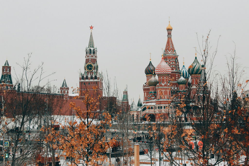 Vista dos palácios do Kremlin, em Moscou, com suas torres vermelhas e trechos em azul e verde, sob o céu branco de inverno.