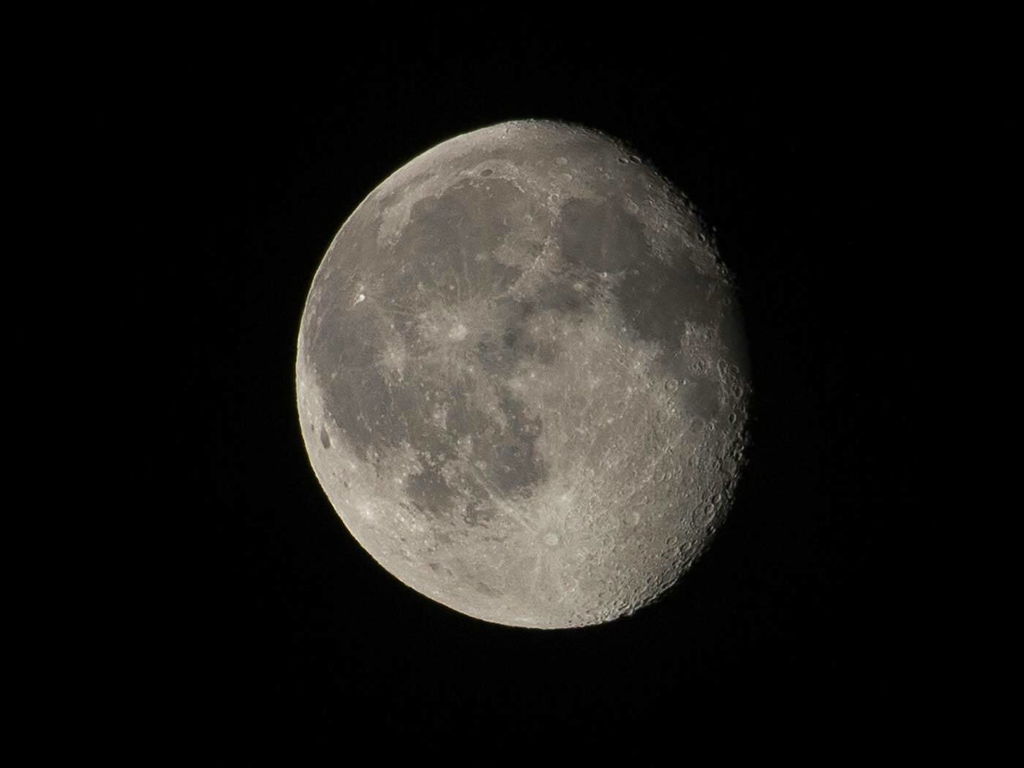 Em fundo preto, do espaço, vê-se mais da metade da lua iluminada.