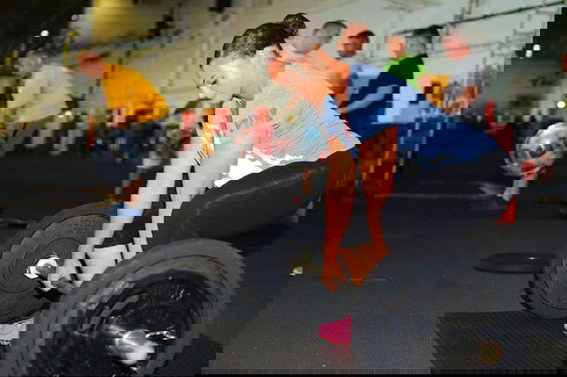 Mulher faz levantamento de peso na academia