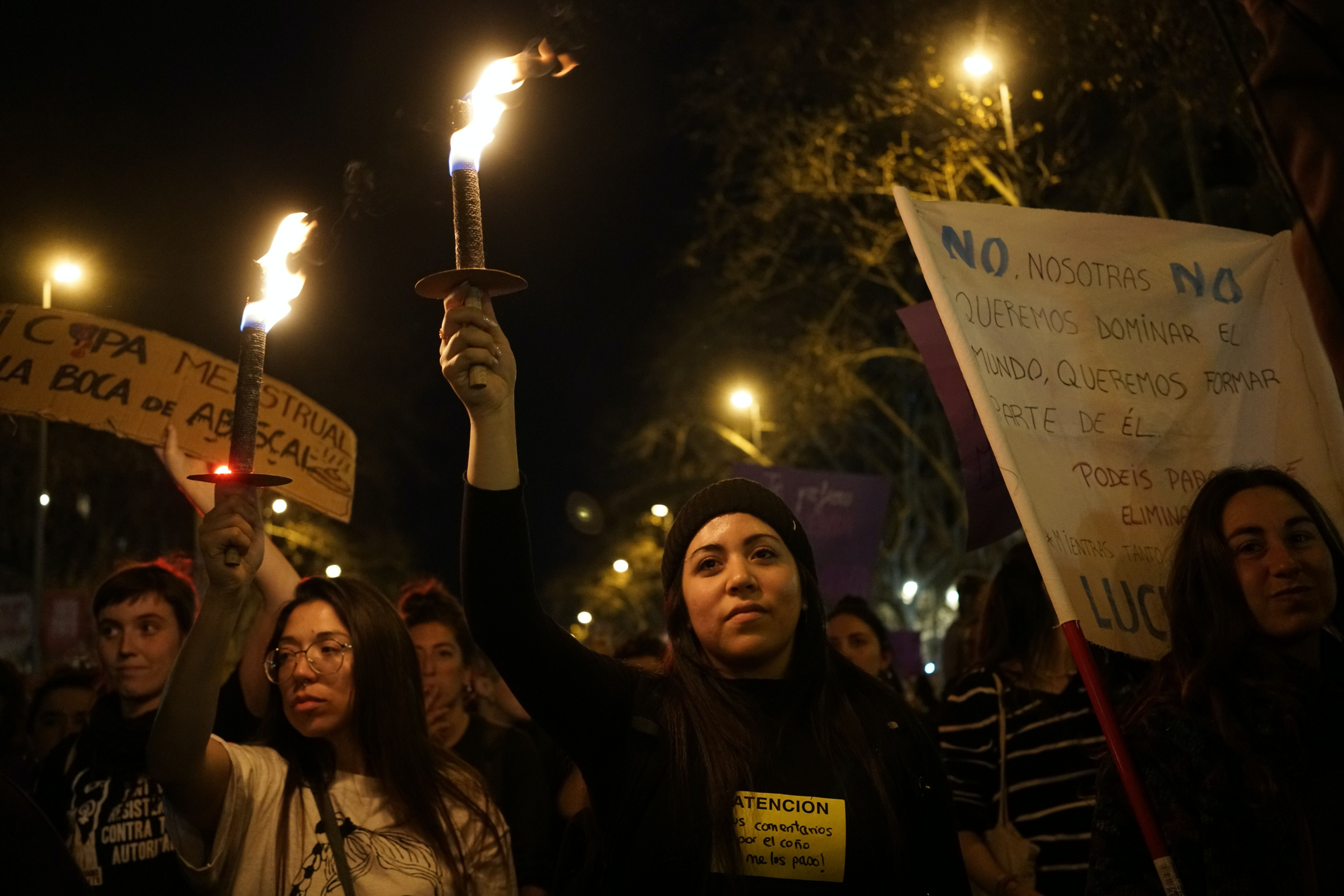 Durante a noite, mulheres com tochas nas mãos participam de uma manifestação feminista.