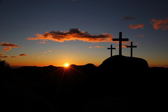 três cruzes no alto de uma montanha ao pôr do sol