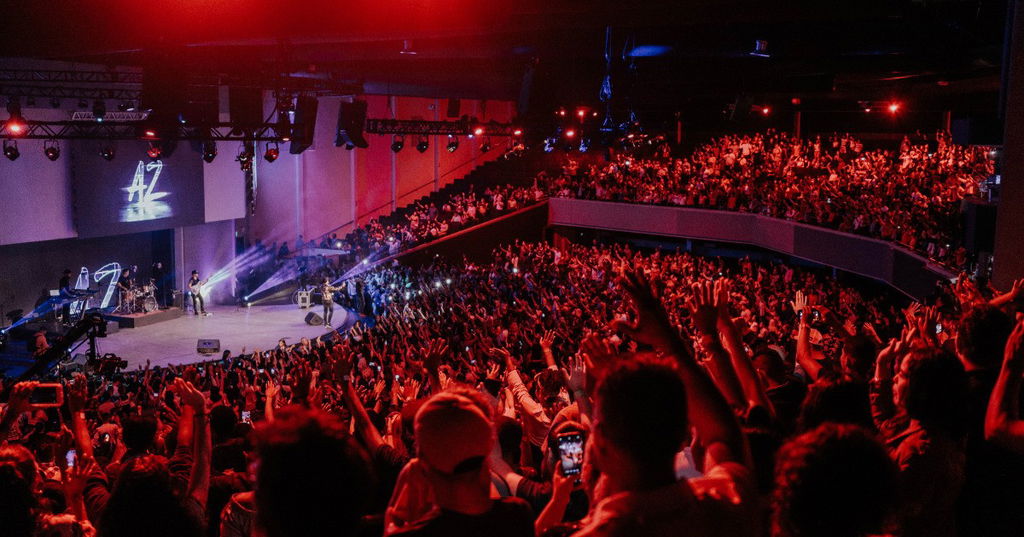 Espetáculo musical em uma arena lotada.