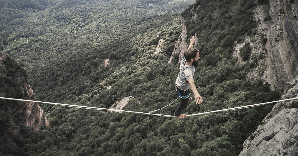 Homem atravessando precipício sobre slackline