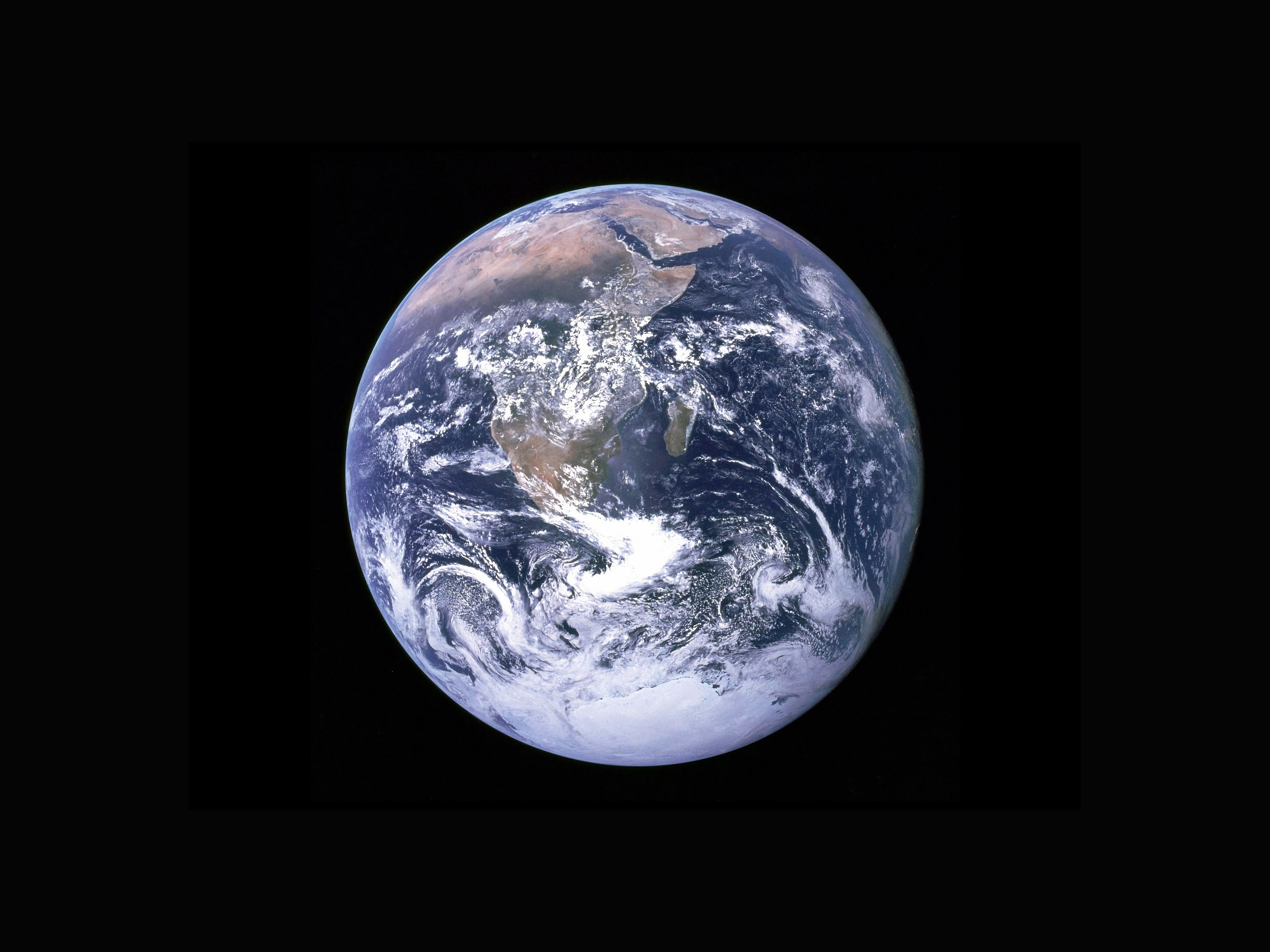 Planeta Terra de cor azul coberto por nuvens brancas visto no espaço.